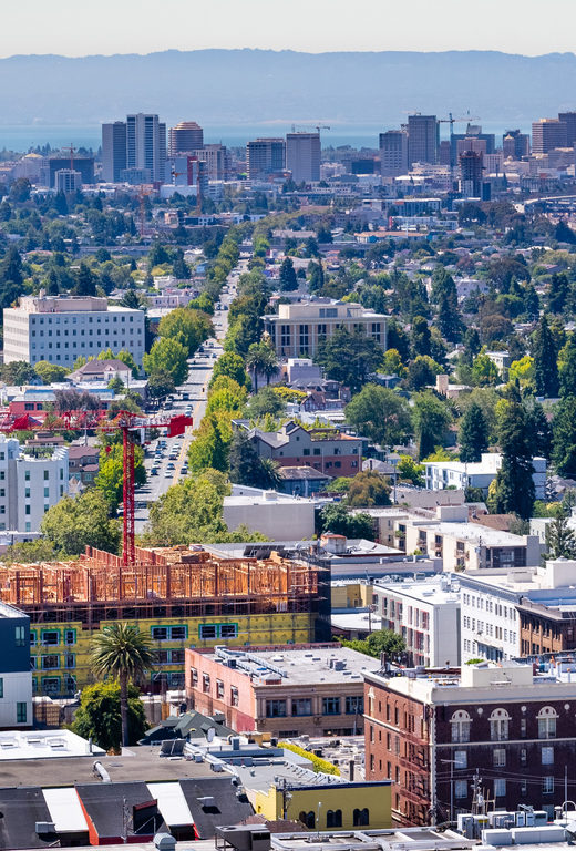 Aerial view of Berkeley and north Oakland on a sunny day; downtown Oakland in the background; buildings in UC Berkeley in the foreground; San Francisco bay, California