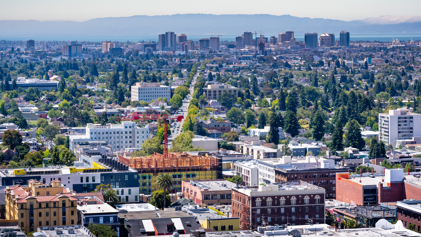 Aerial view of Berkeley and north Oakland on a sunny day; downtown Oakland in the background; buildings in UC Berkeley in the foreground; San Francisco bay, California