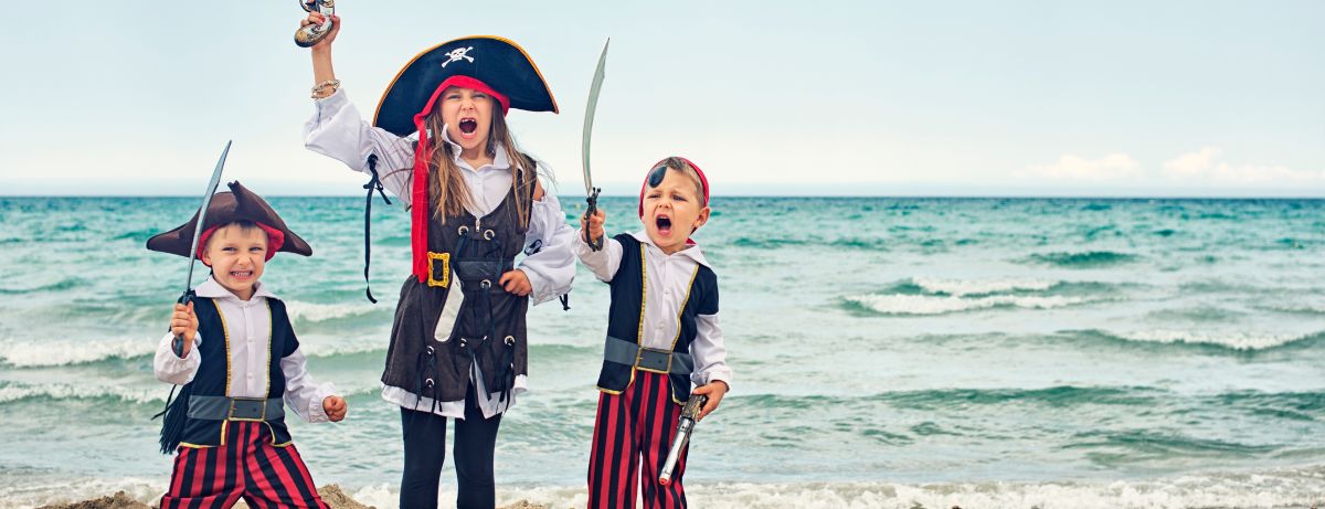 three kids dressed as pirates on a beach